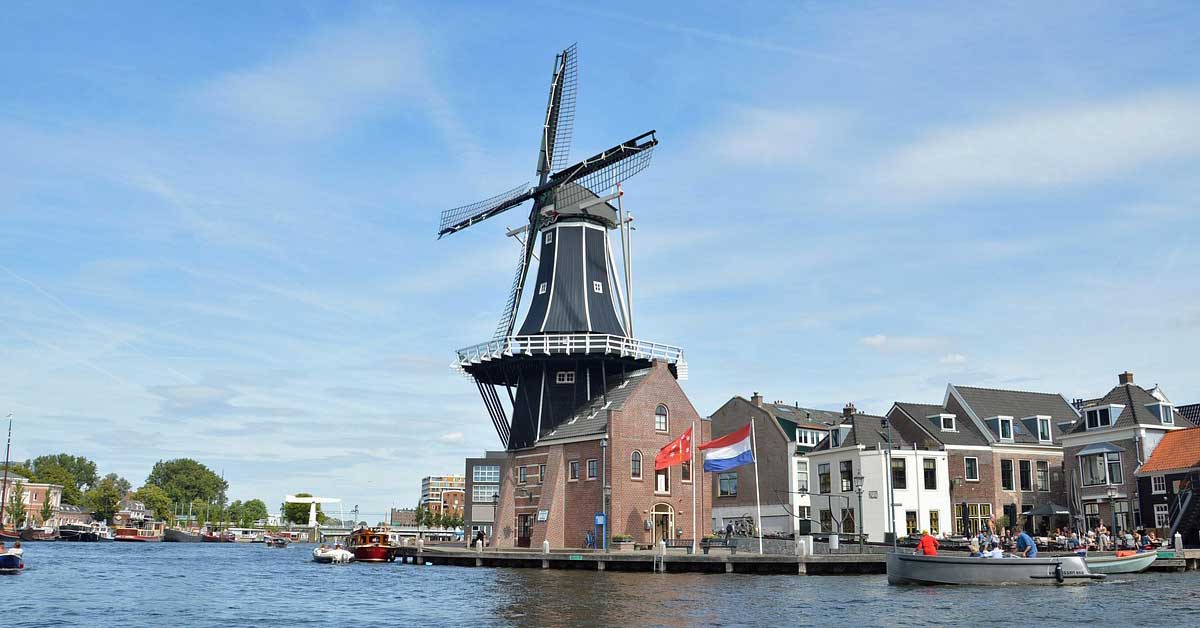 A windmill stands by the river, adjacent to a row of buildings in Haarlem, near Tierney's Irish Pub. Photo: Hendrik from Pixabay.